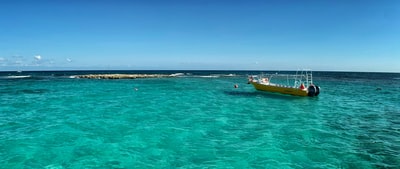 During the day, yellow and red boat is sailing on the sea
